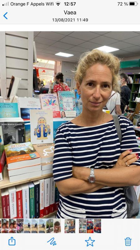 Photo d'Anne Bassi, l'autrice est devant son livre dans la librairie de l'ile d'Oléron.
